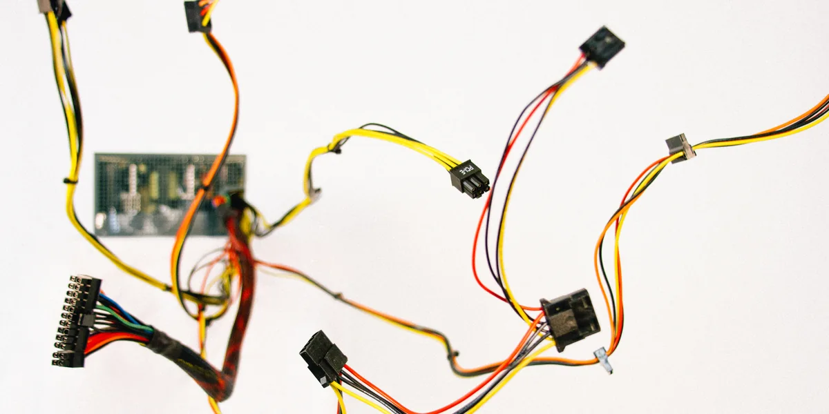 Un mănunchi de cabluri colorate și un mic circuit pe fundal alb, conectori împrăștiați în toate direcțiile