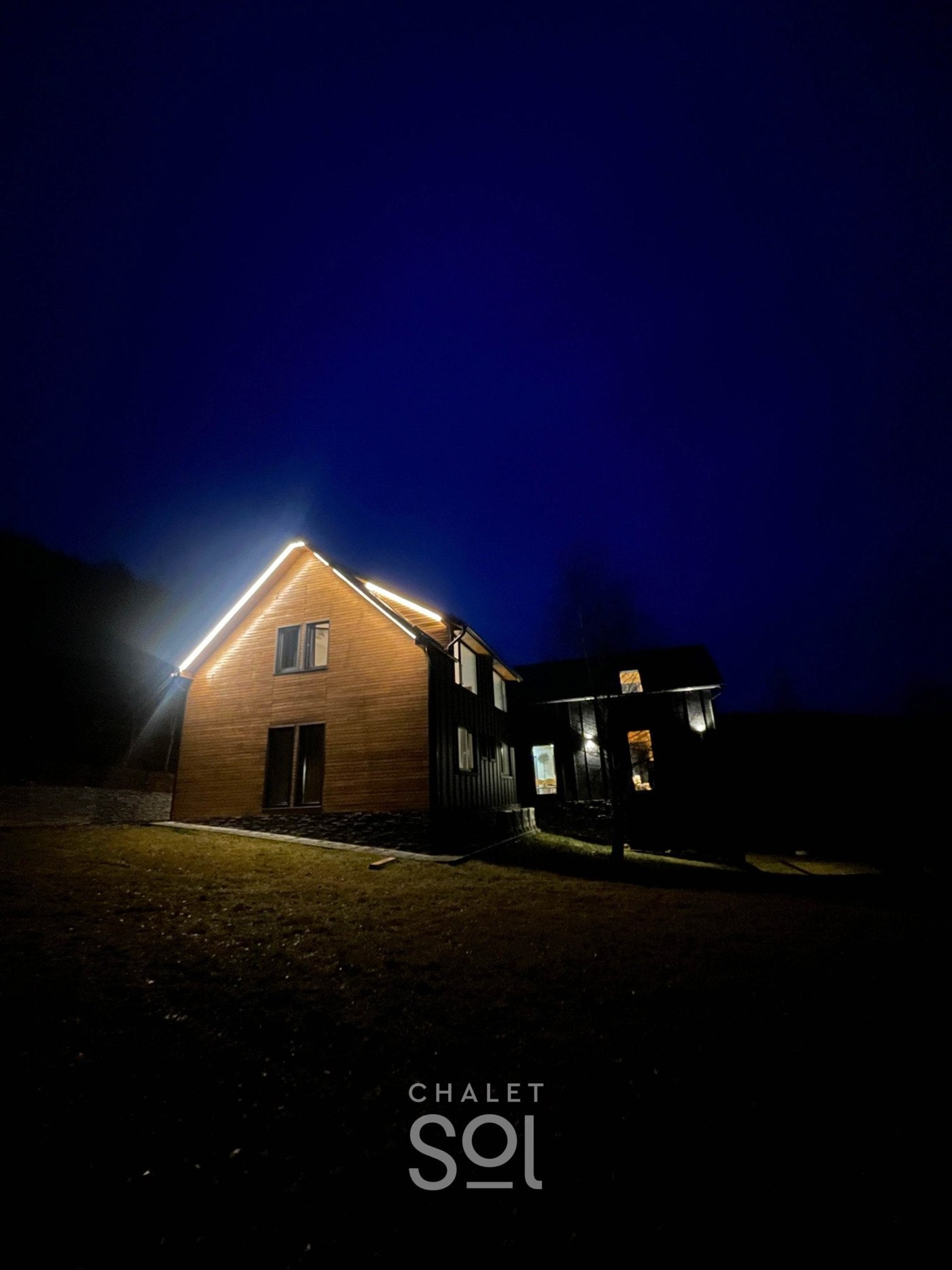 Chalet Sol after dark — the whole house lit against the valley